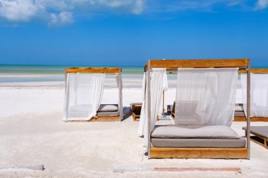 Beyaz perdeli zarif ahşap plaj kabinleri el değmemiş Isla Holbox kumları üzerinde turkuaz Karayip Denizi 'ne bakıyor..