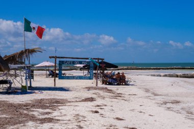 Holbox, Meksika 9 Şubat 2025: Cafe del Mar adında bir köy plaj salonu, Meksika bayrağı dalgalanan şemsiyeler altında sakin Karayip sahillerinin beyaz kumlarına kurulmuş güneşlenenleri karşılıyor.