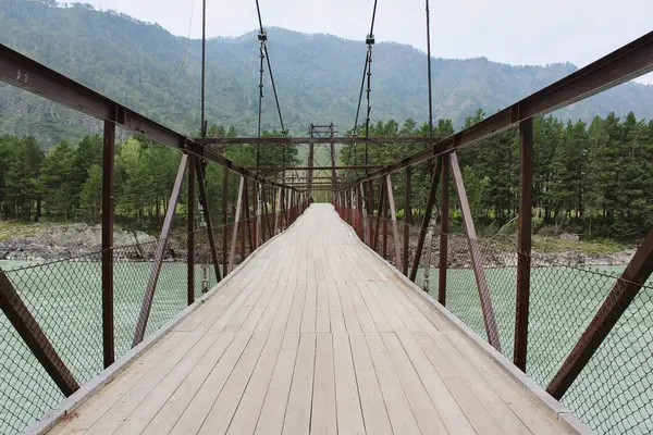 stock image wooden decking on an iron suspension bridge for pedestrians across the river.
