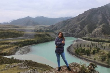 Chuya ve Katun 'un farklı renklerde iki nehrin birleştiği yerde duran genç bir kadın. Dağ manzarası, Altai Cumhuriyeti, Rusya. Yüksek kalite fotoğraf