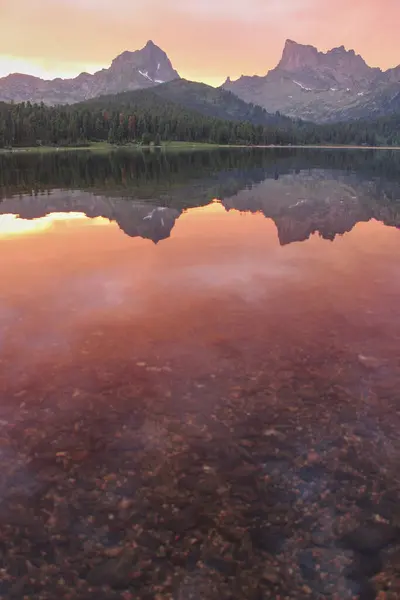 The mountains are reflected in the crystal clear water of the lake at sunset. Selective focus