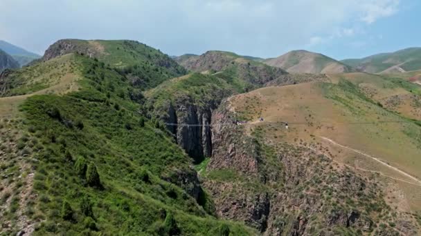 游客沿着连接岩石峡谷两侧的悬索桥步行 大受欢迎的鸽子瀑布落在比什凯克市附近 吉尔吉斯斯坦的旅游业 高质量的4K野性无人机镜头 — 图库视频影像