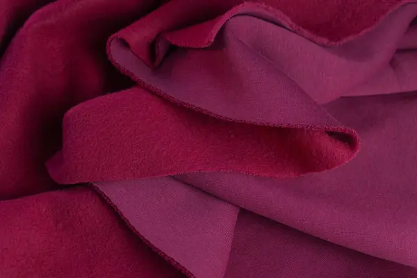 stock image Piece of fabric lies in beautiful waves. layers of French terry pink amaranth textile. cut for sewing