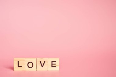 Sevgililer Günü konsepti, 14 Şubat tarihli. Aşk kelimesi, pembe arkaplanda fotokopi alanı olan bireysel harflerden oluşur.. 