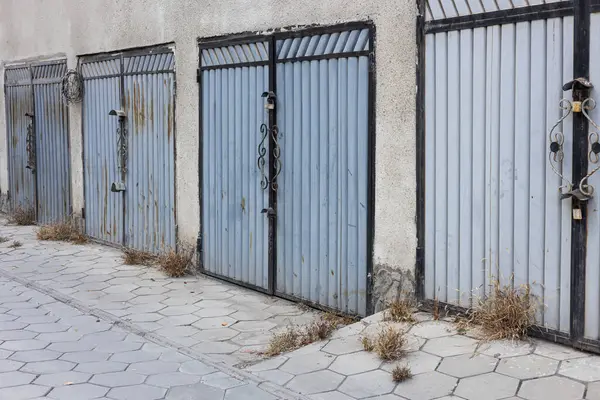 Bir apartmanın avlusundaki araba park yerlerinin girişleri. Bir sürü metal garaj kapısı var. Garaj kooperatif