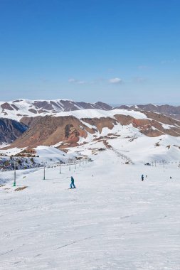 Otelde geniş bir kayak pisti var. Kayakçılar ve snowboardcular karlı dağın yamacından aşağı yuvarlanıyorlar. Kış tatili aktivitesi, aşırı boş zaman. Doğal kış manzarası, güneşli gün mavi gökyüzü, tepenin üstünde