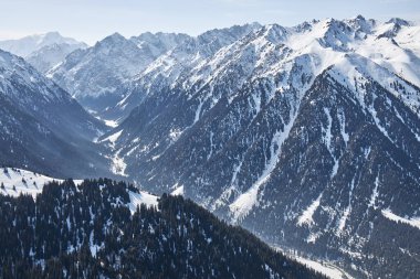 Karla kaplı yüksek dağların tepesinden panoramik manzara. Karakol Gorge, Kırgızistan 'da kayak merkezi. Kış doğal manzarası, dağ sırası.