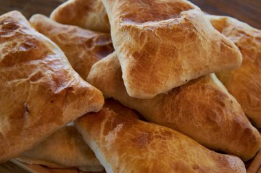 Üçgen şeklinde puf böreği. Taze pişmiş yiyecekler: Etli samsa ya da patatesli yakın çekim, yan görüş. Lezzetli Asya yemekleri, geleneksel doğu mutfağı Tacikistan, Özbekistan, Kırgızistan, Kazakistan. 