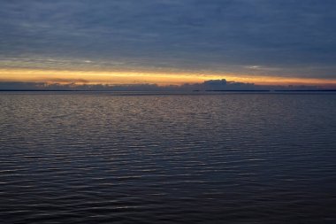 Koyu mavi bulutlar ve parlak turuncu güneş ışığıyla gün batımı. Novosibirsk rezervuarı, Ob Denizi, Ob Nehri üzerindeki yapay gölet. gökyüzü suyu doğal manzara deniz manzarası