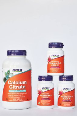 iHerb online mağazasından kavanozlar dolusu kalsiyum sitrat ve D-3 vitamini, Now Foods Company. Sağlıklı gıda, vitamin ve mineraller seti. Gri arka plan. Bishkek, Kırgızistan - 8 Aralık 2023. 