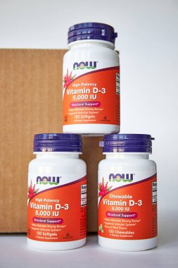 Üç kavanoz D3 vitamini piramidi, Chewable, Now Foods Company, kahverengi karton kutunun yanında. iHerb çevrimiçi mağazasından besin takviyeleri almak, paketleri açmak. Bishkek, Kırgızistan - 8 Aralık 2023
