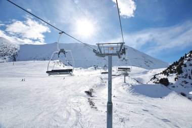 Kırgızistan 'daki Chunkurchak kayak merkezi. Boş teleferik koltukları. Güneşli kış gününde dağ yamacı, mavi gökyüzü. Aktif kayak ve snowboard sporu. Destek sütunu, kablo araba yolculuğu.