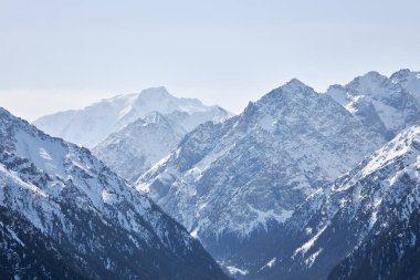 Kırgızistan dağlarında kış. Dağ sırası, karlı tepeler, orman ve dağlık arazi arasındaki sınır. Doğal manzara arka planı. Karakol vadisi manzarası. Orta Asya. 
