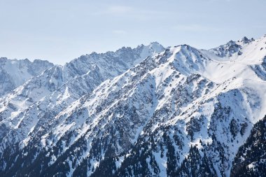 Karakol vadisi manzarası. Kırgızistan dağlarında kış. Dağ sırası, karlı tepeler, orman ve dağlık arazi arasındaki sınır. Doğal manzara arka planı. Orta Asya. 