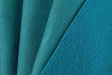  Fransız Terry Turkuaz Tekstil 'in önü ve arkası. Bir kumaş parçası güzel dalgalarda yatıyor. Dikiş için kesilmiş. Mavi malzeme arka planı. safir rengi polipamuk pamuk polyester