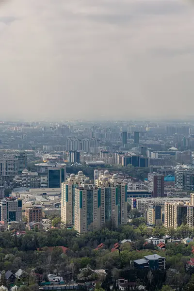 Kazakistan Cumhuriyeti, Orta Asya, Almatı şehri manzarası. İlkbaharda şehir manzarası, yüksek ve alçak binalar, konut binaları, ofisler ve iş merkezleri. Kasabanın altını üstüne getirin. ekoloji