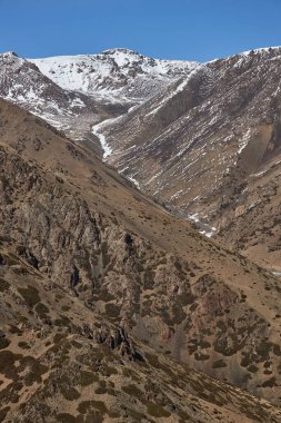 Kırgızistan dağları. Karlı tepe yamaçlı bahar dağı manzarası. Orta Asya, vahşi doğa.