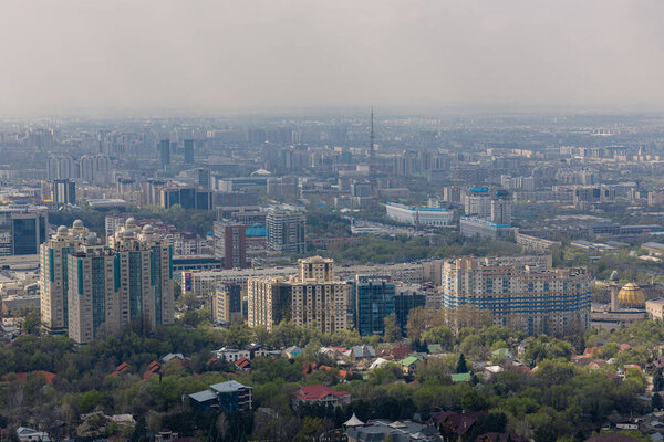 Republic of Kazakhstan, Central Asia. City architecture, urban space. Panoramic view on Almaty from mount Kok Tobe park. Cityscape at spring day. Haze smog above town, ecology problem.