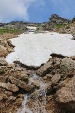 Dağlardaki bir yığın kardan akan taşların arasından bir dere akar. İçme suyu kaynağı: