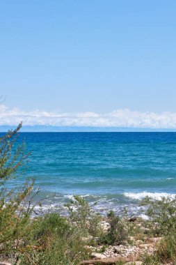 Büyük Issyk-Kul Gölü 'nün güney kıyısında, Kırgızistan' da yaz tatili. Açık mavi gökyüzü, zümrüt renkli gölet suyu, küçük dalga. Kirgiziya seyahat rotası