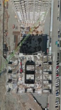 İnşaat alanı, yüksek bina ve kazı işleri, inşaat halindeki birkaç bina. Yukarıdan aşağıya drone görüntüsü. İnşaatın farklı aşamalarındaki çok katlı binalar. Konut binası