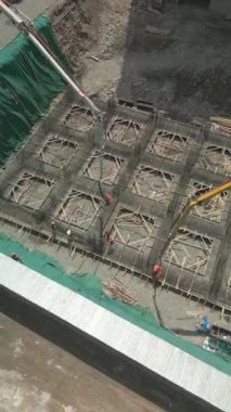 İnşaat alanındaki işçiler iki beton pompa kamyonu kullanarak binanın tabanına çimento döküyorlar. Binanın beton zeminleri dökülüyor. Çukurda çalış. Hava aracı görüntüleri. Bishkek, Kırgızistan - 21 Haziran 2024