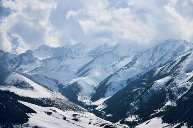 Panoramik manzara karla kaplı yüksek dağlar. Kırgızistan 'daki Chunkurchak Vadisi. Kış doğal manzarası, dağ silsilesi duvar kağıdı. Beyaz bulutlu destansı gökyüzü
