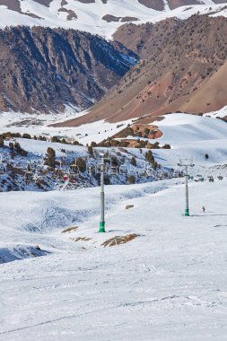 İnsanlar bir teleferikle dağın tepesine çıkıyorlar. Kayak merkezi kış aktivitesi. Chunkurchak, Kırgızistan, Kirgiziya. Kayak direği, dağ yamacında kar, kayakçılar, snowboardcular