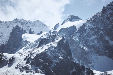 Karlı dağ zirveleri, kaya. Uçsuz bucaksız arazi, dik yamaçlar. Ala-Archa Ulusal Parkı, Kırgızistan.