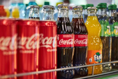 Rafta farklı marka gazozlar var. Coca Cola, Fanta, yukarı 7. Alüminyum kutular ve çeşitli boyutlarda cam şişeler. Meşrubat başyazısı, popüler karbonatlı içecekler. Bishkek, Kırgızistan - 26 Mayıs 2023