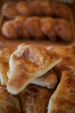 Taze pişmiş yiyecekler: etli samsa, üzerine beyaz susam tohumları serpiştirilmiş ahşap tabakta yatıyor. Asya yemekleri, geleneksel doğu mutfağı Tacikistan, Özbekistan, Kırgızistan. Üçgen puf böreği samosa