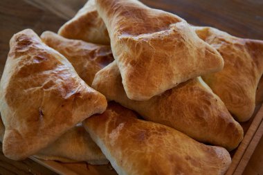 Lezzetli Asya yemekleri, geleneksel doğu mutfağı Tacikistan, Özbekistan, Kırgızistan, Kazakistan. Üçgen şeklinde puf böreği. Taze pişmiş yiyecekler: etli ve patatesli samsa yakın plan, yan görüş. 