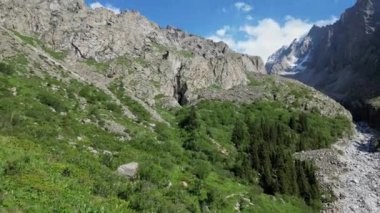 İnanılmaz dağ manzarası, yaz doğal manzarası, karlı tepeler, bulutlu mavi gökyüzü. Ala-Archa Ulusal Parkı, Kırgızistan. Yolculuk güzergahı, Aksai şelalesi. Hava aracı 4k görüntüsü