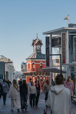 İnsanlar tarihi bir anıt olan Saat Kulesi rıhtımının yakınında yürüyorlar. Gün batımından önceki akşam caddesi turistlerle doludur. Cape Town, Güney Afrika - 21 OCT 2023