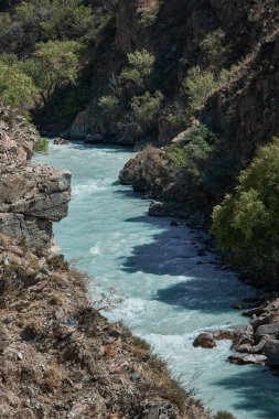 Bereketli yeşilliklerle çevrili kayalık bir kanyondan geçen bir nehir güzel, resimsel bir manzara yaratıyor.