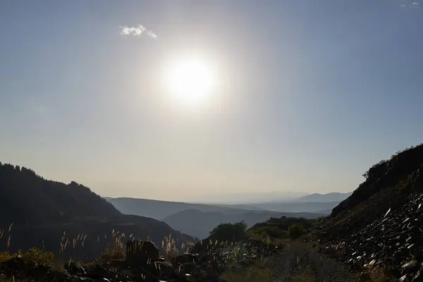 Berrak mavi bir gökyüzünün altında uzanan görkemli dağların nefes kesici bir manzarası var. Güneş ışıl ışıl parlıyor. Mükemmel bir günde, parlak güneş ışığı altında şaşırtıcı derecede güzel bir dağ manzarası.