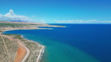 Kıyı manzarası. Kumsal ve kayalık çıkıntılar, Kırgızistan 'ın ana merkezi olan Issyk-Kul Gölü' nün sonsuz genişliği. Birkaç beyaz bulutlu açık gökyüzü