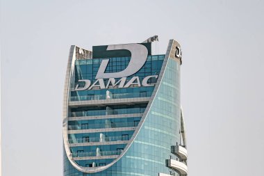 Yüksek binadaki Damac geliştirme şirketi logosu. DAMAC Maison Distinction otel kulesi. Camdan gökdelenin çatısında. Dubai, BAE - 1 NOV 2023