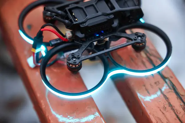 Çerçevenin etrafında mavi LED ışıklandırmalı FPV insansız hava aracı, motorlar açık