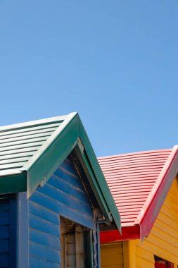 Capetown, Güney Afrika 'daki Muizenberg plajında rengarenk yazlık evler, hamam kutuları, masaları değiştirmek.