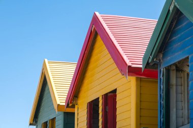 Capetown, Güney Afrika 'daki Muizenberg plajında rengarenk yazlık evler, hamam kutuları, masaları değiştirmek.