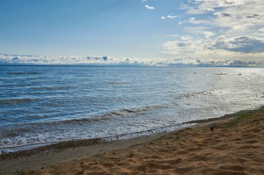 Issyk-Kul Gölü, kumlu plaj, büyük göl kıyısı, Kırgızistan 'da yaz tatili. Göletin mavi renkli suyu, küçük dalga. Kirgiziya 'nın gideceği yer. Bulutlardaki dağlar