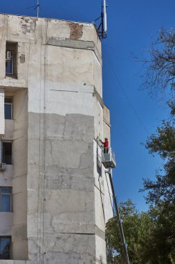 İşçi binanın ön cephesinde tadilat ve onarım için kiraz toplayıcısı kullanıyor.