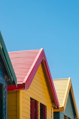 Capetown, Güney Afrika 'daki Muizenberg plajında rengarenk yazlık evler, hamam kutuları, masaları değiştirmek.