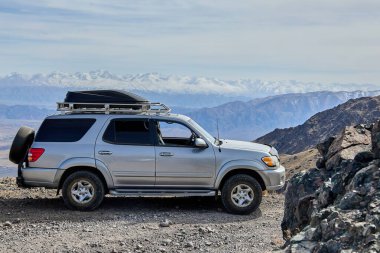 Dağlarda tavan rafı olan gri renkli Toyota Sequoia. Kırgızistan - 11 Nisan 2024.