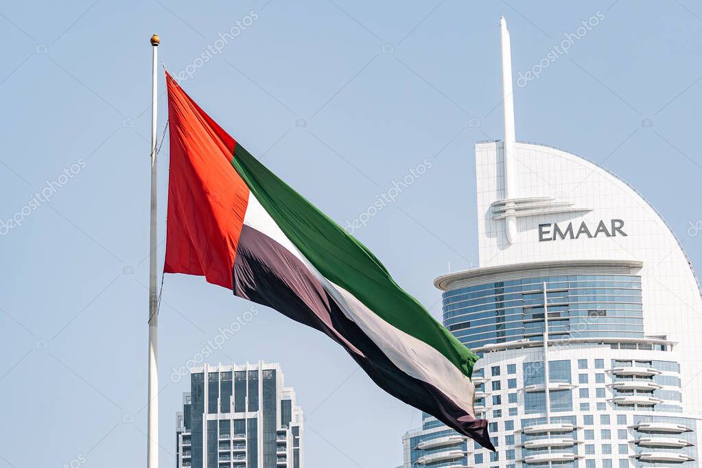 Flag of the United Arab Emirates and Emaar Properties logo on white building. Dubai, UAE - 01 NOV 2023