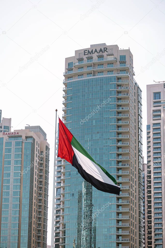 Flag of the United Arab Emirates and Emaar Properties logo on white building. Dubai, UAE - 01 NOV 2023