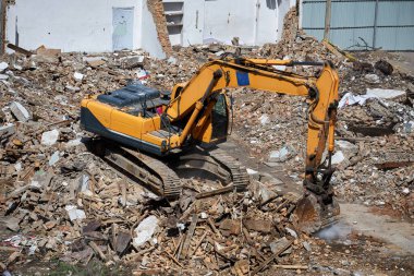 Kazıcı evin enkazının üzerinde duruyor. Sökülme işlemi, eski binanın yıkılması, harap olmuş konutların tahrip edilmesi.