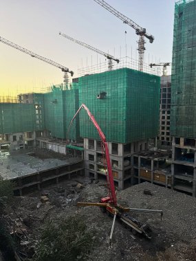 İnşaat alanına beton pompa döken bir kamyon. Çok katlı bir binada inşaat işi var.. 