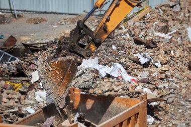 Kazı kovası, kamyonun cesedine inşaat enkazı döker, yakın plan. İnşaat atıklarının kaldırılması